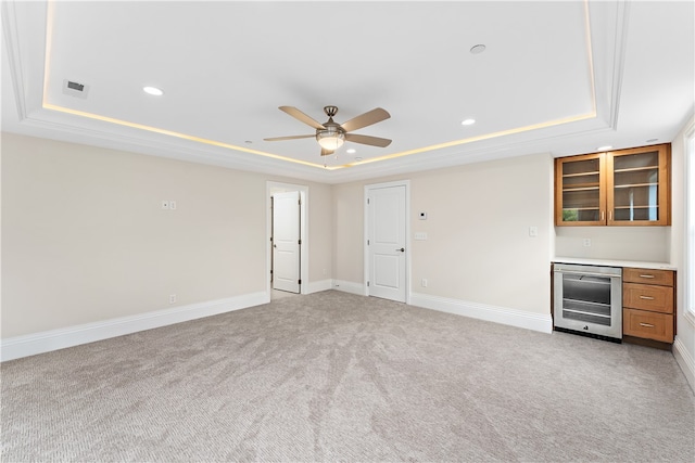 interior space featuring a tray ceiling, light carpet, ceiling fan, and wine cooler