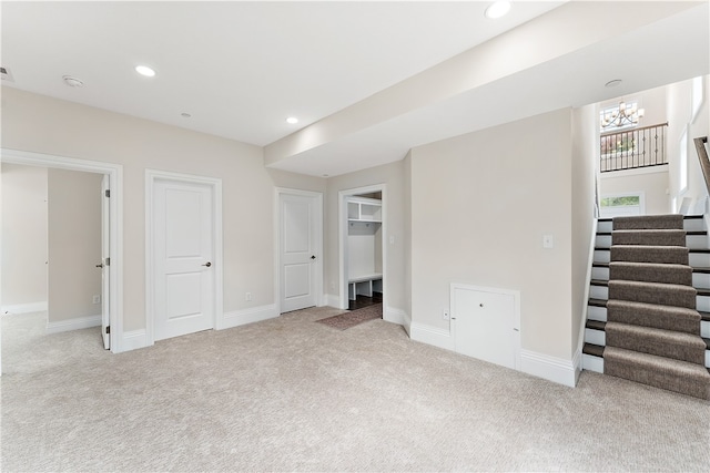 basement with light carpet and a notable chandelier