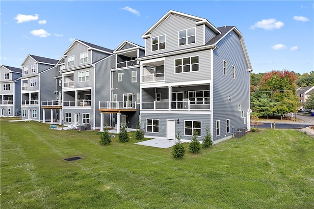 back of property with a balcony, a yard, central air condition unit, and a patio area