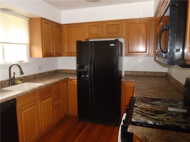 kitchen with brown cabinetry, a sink, black appliances, and dark wood-style flooring