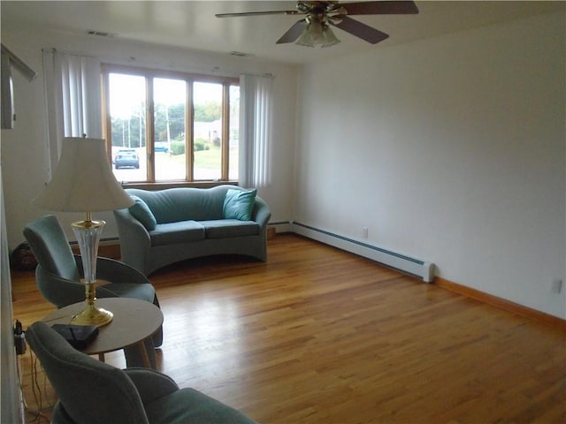 living room featuring light wood-type flooring, a ceiling fan, baseboards, and a baseboard radiator