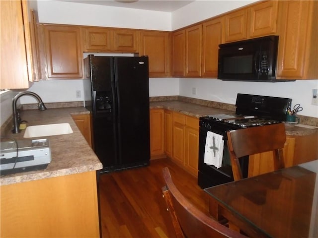 kitchen with light countertops, a sink, black appliances, brown cabinetry, and dark wood-style flooring