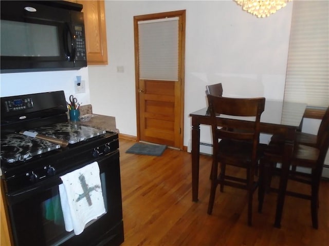 kitchen with light wood-style flooring, baseboards, and black appliances