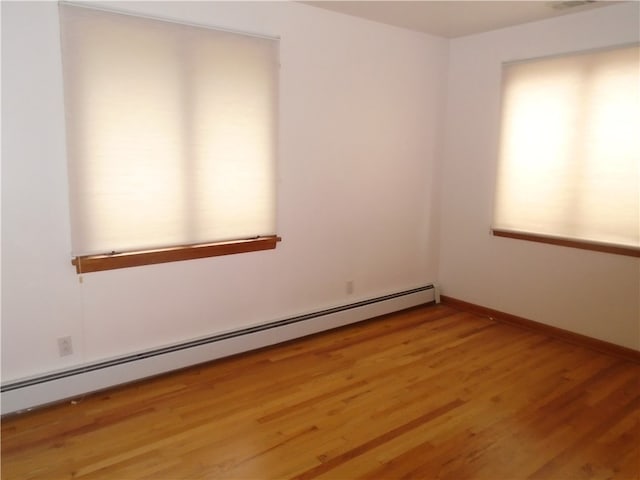 empty room with light wood-type flooring and a baseboard radiator