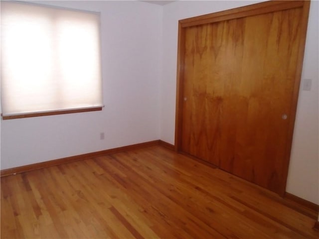spare room with baseboards and light wood-style floors