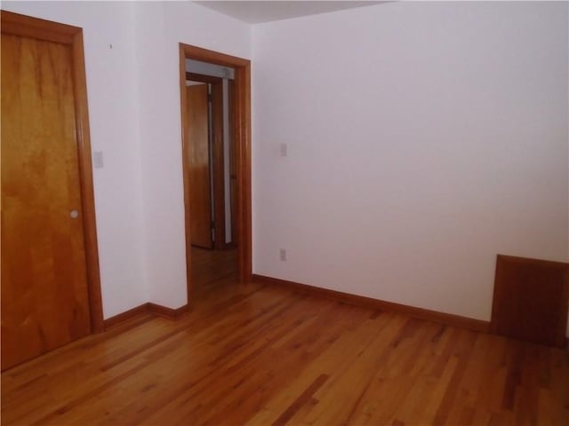 spare room with baseboards and light wood-style floors