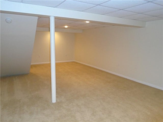 finished below grade area with light carpet, a paneled ceiling, and baseboards