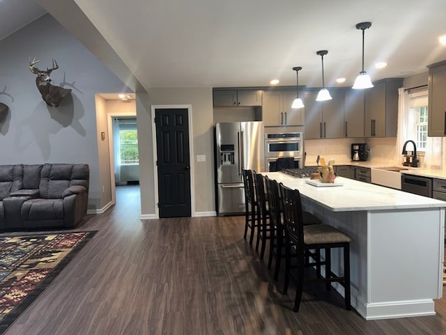 kitchen featuring gray cabinets, a center island, tasteful backsplash, stainless steel appliances, and decorative light fixtures