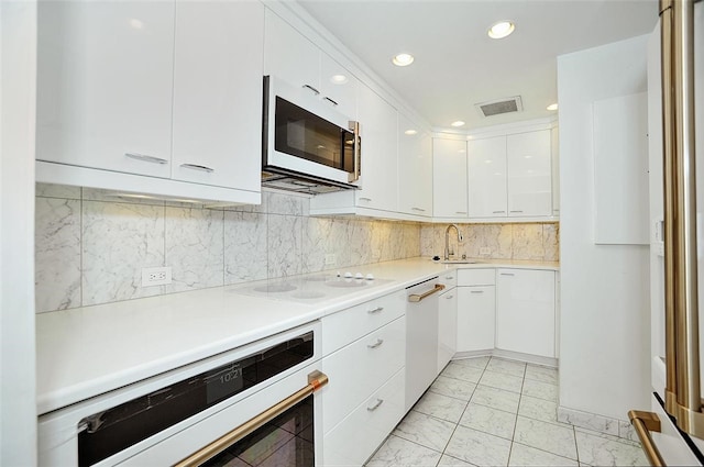 kitchen with decorative backsplash, white appliances, white cabinetry, and sink