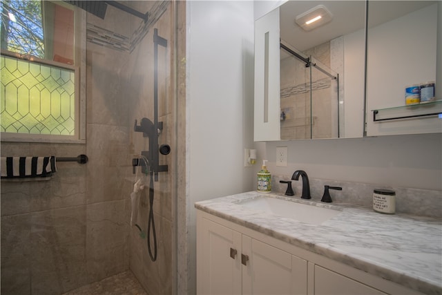 bathroom featuring a shower with door and vanity