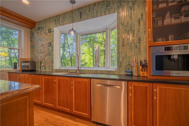 kitchen featuring sink, appliances with stainless steel finishes, hanging light fixtures, and light hardwood / wood-style floors