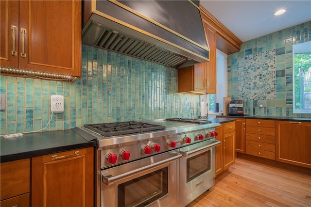 1487 Beaver Rd, Sewickley, PA 15143 - kitchen with brown cabinets, wall chimney exhaust hood, light wood-style flooring, range with two ovens, and tasteful backsplash