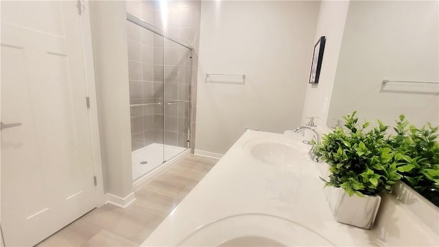 bathroom featuring a shower stall, baseboards, double vanity, and tile patterned flooring