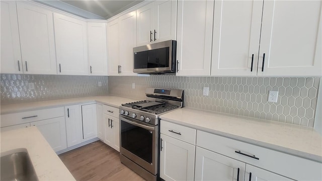 kitchen featuring stainless steel appliances, white cabinets, tasteful backsplash, and light hardwood / wood-style flooring