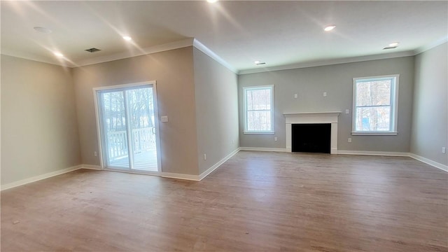 unfurnished living room featuring crown molding, wood finished floors, baseboards, and a fireplace
