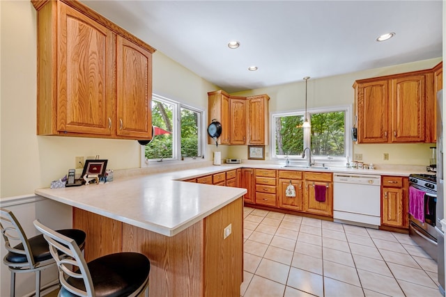 kitchen featuring hanging light fixtures, kitchen peninsula, dishwasher, stainless steel stove, and a breakfast bar area