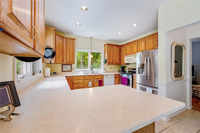 kitchen featuring light tile patterned flooring, kitchen peninsula, pendant lighting, stainless steel appliances, and sink