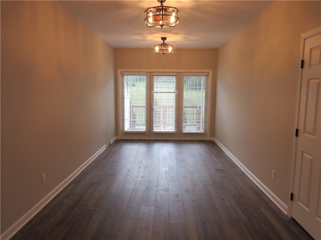 unfurnished room with a chandelier and dark hardwood / wood-style flooring