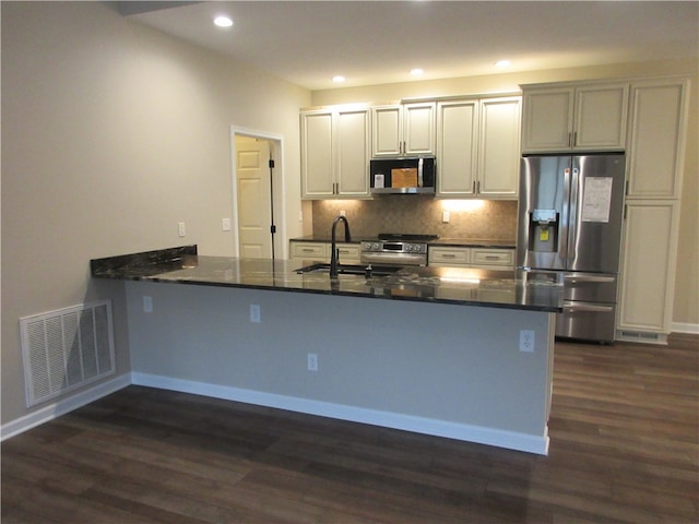 kitchen featuring kitchen peninsula, appliances with stainless steel finishes, sink, and dark hardwood / wood-style flooring