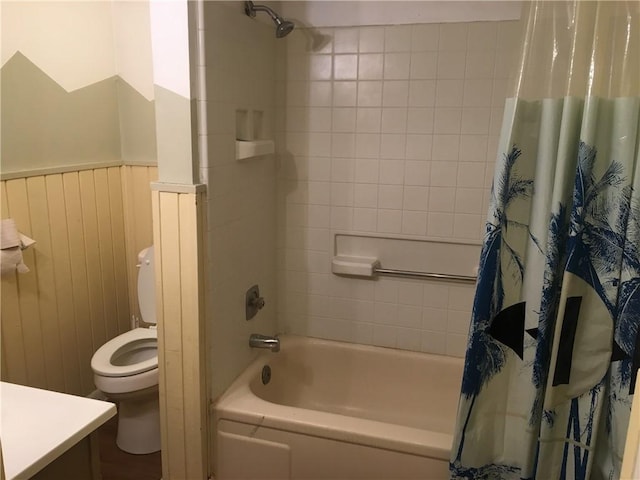 bathroom with wainscoting, shower / bath combo, vanity, and toilet