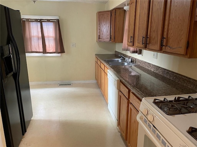 kitchen with a sink, visible vents, baseboards, white appliances, and brown cabinets