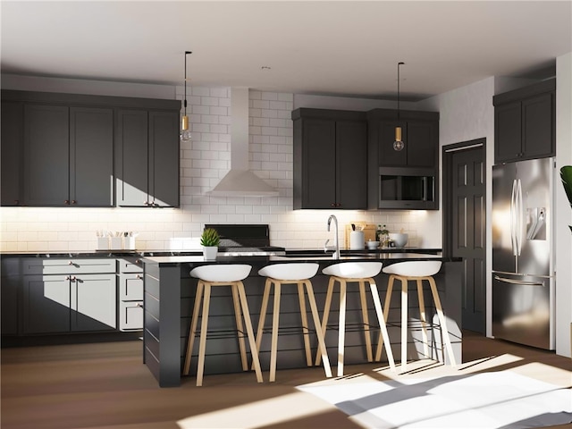 kitchen with a kitchen island with sink, backsplash, wall chimney range hood, stainless steel appliances, and a breakfast bar area