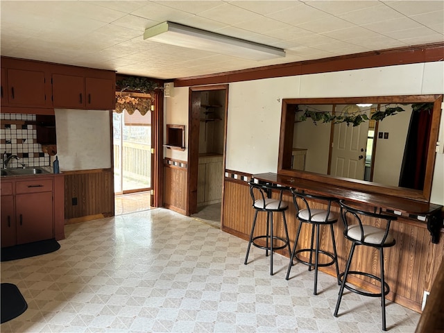 kitchen featuring wood walls, a kitchen bar, and sink