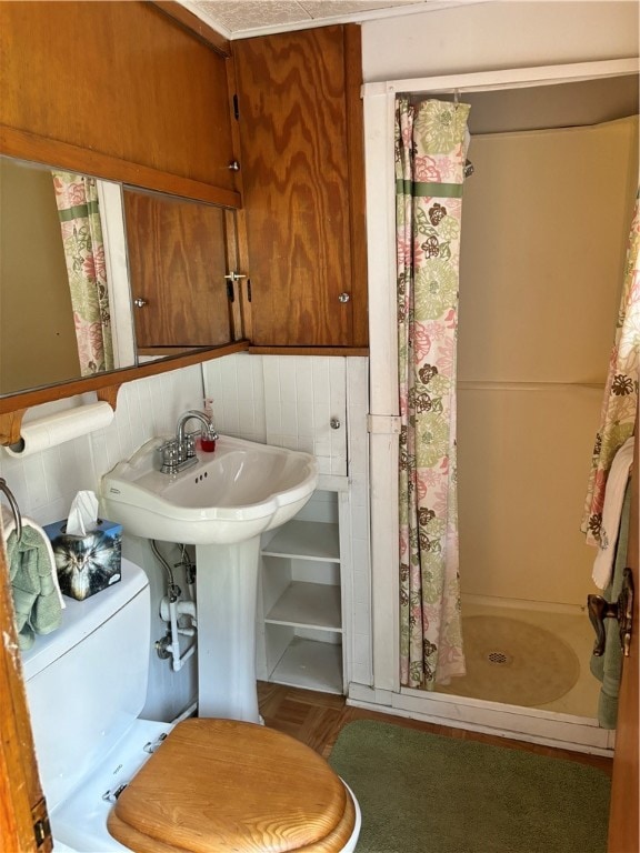 bathroom featuring a shower with shower curtain, parquet flooring, and toilet