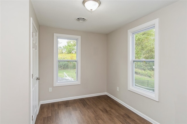 spare room featuring dark hardwood / wood-style floors and a healthy amount of sunlight