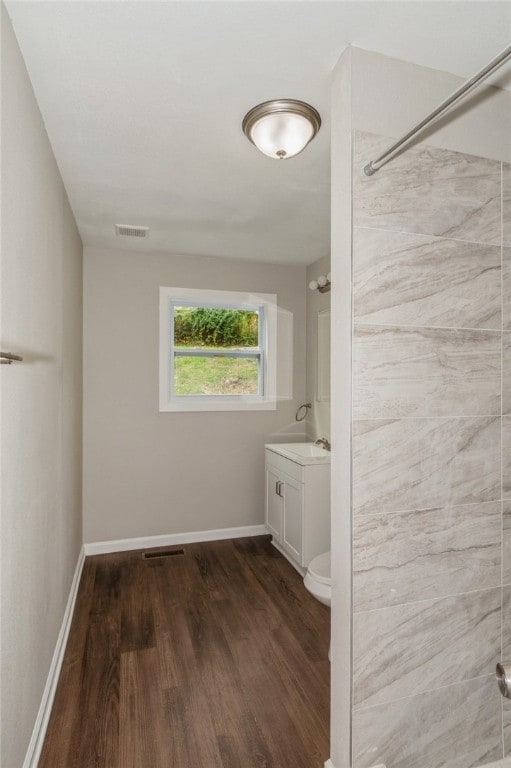 bathroom with walk in shower, hardwood / wood-style floors, vanity, and toilet