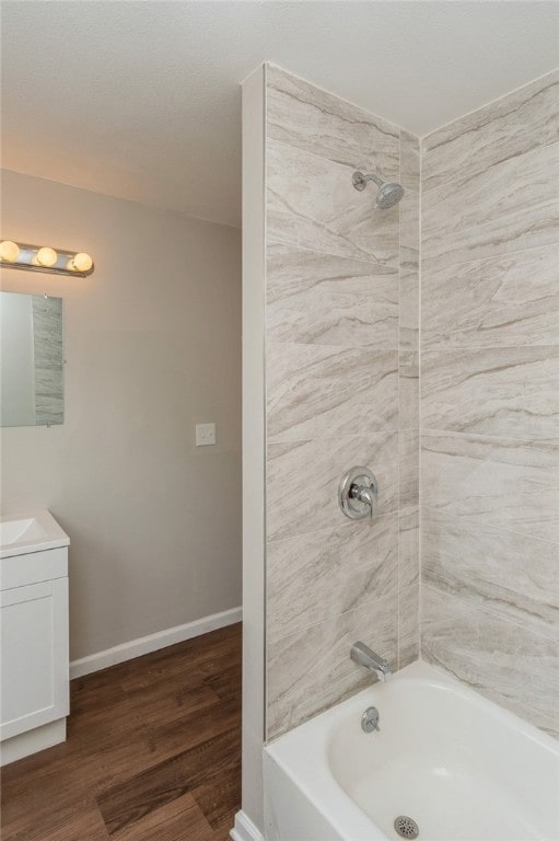 bathroom featuring wood-type flooring, tiled shower / bath combo, and vanity