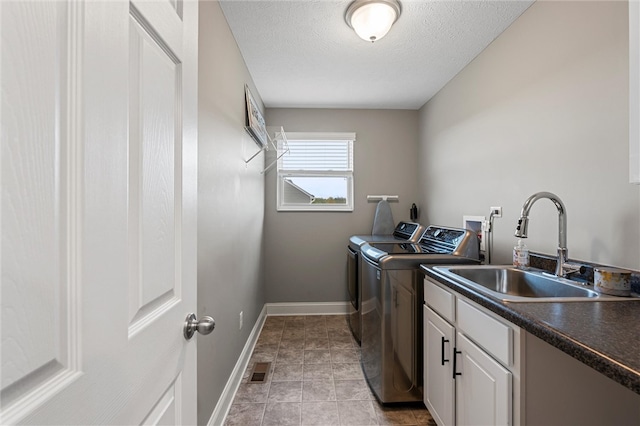 laundry area featuring light tile patterned flooring, sink, a textured ceiling, cabinets, and independent washer and dryer