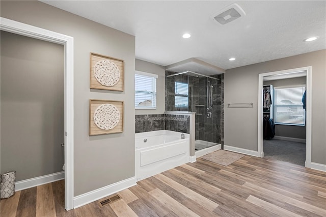 bathroom with hardwood / wood-style flooring, a healthy amount of sunlight, toilet, and plus walk in shower