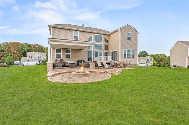 rear view of property featuring a fire pit, a yard, and a patio