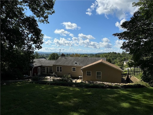 rear view of house with fence and a lawn