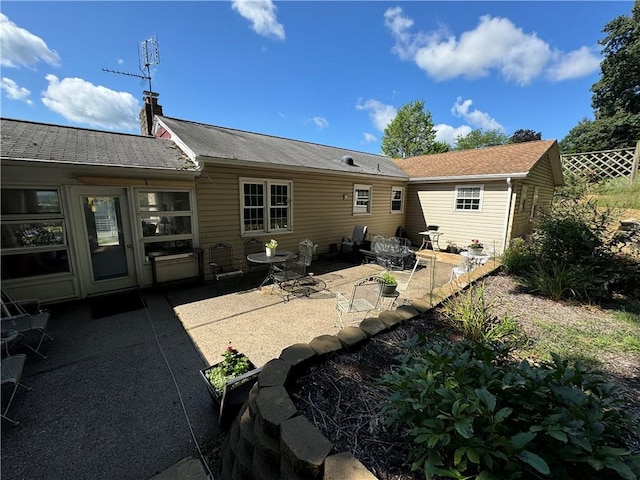 rear view of house with a patio area, fence, and a chimney