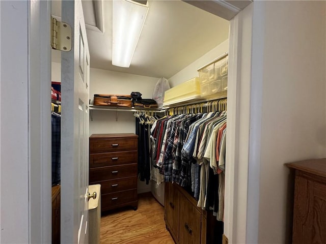 walk in closet featuring light wood-style flooring and lofted ceiling