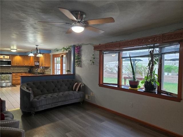 living room with ceiling fan with notable chandelier and hardwood / wood-style floors