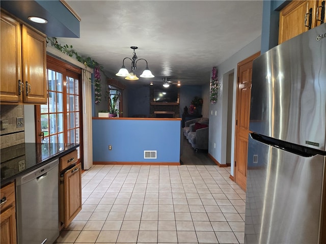 kitchen featuring appliances with stainless steel finishes, hanging light fixtures, decorative backsplash, light tile patterned floors, and a chandelier