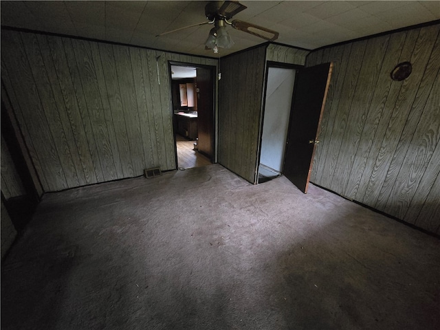 unfurnished bedroom featuring wood walls and ceiling fan