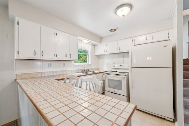 kitchen featuring white appliances, tile counters, white cabinetry, and sink