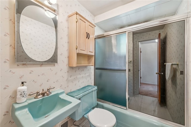 full bathroom featuring bath / shower combo with glass door, toilet, and sink