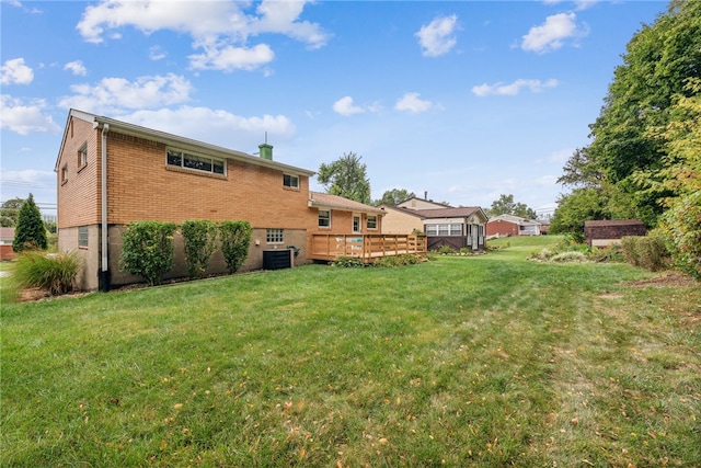 back of property featuring a lawn, a deck, and central AC