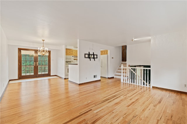 unfurnished living room with light hardwood / wood-style flooring, french doors, and a chandelier