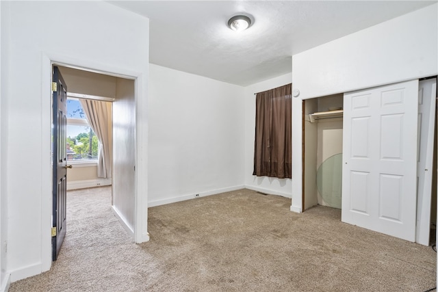 unfurnished bedroom featuring light colored carpet and a closet