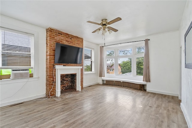 unfurnished living room with light hardwood / wood-style flooring, cooling unit, ceiling fan, and a fireplace