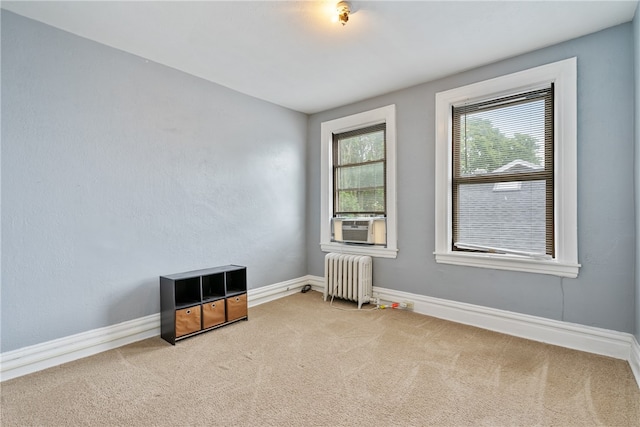 unfurnished room featuring radiator heating unit and light carpet