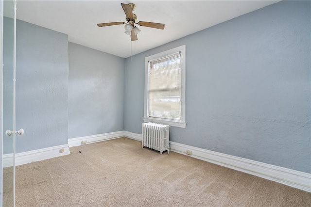 unfurnished room featuring ceiling fan, light colored carpet, and radiator heating unit