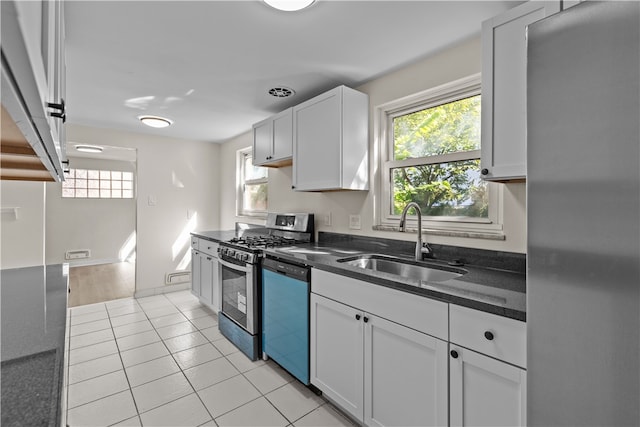 kitchen with light tile patterned flooring, appliances with stainless steel finishes, sink, and white cabinetry