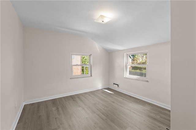 unfurnished room with lofted ceiling and light wood-type flooring